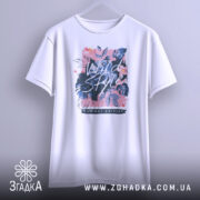 Футболка дикий стиль, біла, підвішена на вішалці, фон світло-сірий, принт з квітами та написом 'Wild Style', видно округлі краї рукавів.