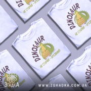 Футболка динозавр не старий. Білий колір, зображена з фронтального ракурсу на манекені. Фон світло-сірий, принт з веселим динозавром та написом 'НЕ СТАРИЙ - АРХІВНИЙ!' у коричневих тонах.