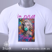 Футболка дивa стиль Мерілін, біла, складена на столі, фон світло-сірий, принт з портретом жінки з жувальною гумкою, текст 'i'm DIVA' і 'Marilyn' яскравими літерами, на комірці зелена етикетка.