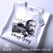 Футболка Джозеф Конрад білого кольору, розкладена на поверхні, фон світлий, принт з портретом Джозефа Конрада та текстом, на футболці є етикетка з зеленим шнурком.