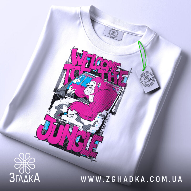 Футболка джунглі стиль, біла, зображена зверху, на фоні світло-сірого градієнту, принт з малюнком горили в рожевих тонах та текстом 'WELCOME TO THE JUNGLE', з етикеткою зеленого кольору.