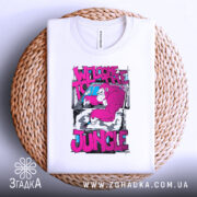 Футболка джунглі стиль, біла, зображена зверху, на фоні плетеного кошика, принт з малюнком горили в рожевих тонах та текстом 'WELCOME TO THE JUNGLE', складена акуратно.