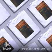 Футболка електро крик кіт білого кольору, зображена з фронтального ракурсу на манекені, фон нейтральний, принт з чорним котом з великими жовтими очима на фоні абстрактного пейзажу з червоними і жовтими відтінками.