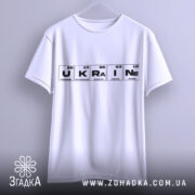 Футболка елементи України, біла, підвішена на вішалці, фон світло-сірий, принт з елементами таблиці Менделєєва, слово 'UKRAINE' виділено чорним кольором.