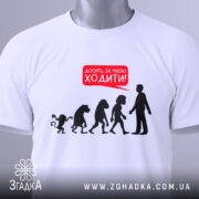 Футболка еволюція досить ходити. Біла футболка, складена на поверхні, фон світло-сірий. Принт з силуетами еволюції та текстом червоного кольору 'Досить за мною ходити!', з зеленим ярликом.