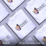 Футболка фея або відьма, білого кольору, зображена з фронтального ракурсу на манекені, фон світлий, принт з ілюстрацією феї та відьми, текст українською мовою.