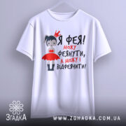 Футболка фея можу феянути, біла футболка на вішалці, з принтом дівчинки-феї в червоній сукні, текст чорного та червоного кольору.