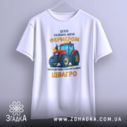 Футболка фермер швагро, біла, зображена з фронтального ракурсу, на фоні світло-сірого градієнту, принт з червоним трактором та жовтим текстом.