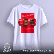 Футболка Ferrari білого кольору, зображена з фронтального ракурсу на вішалці, фон світло-сірий, принт з червоним автомобілем Ferrari 625 TRC Spider 1957, текст 'Thirst for speed' на червоному фоні.