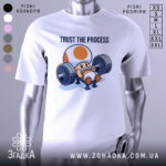 Футболка фітнес настрій, біла, зображена на манекені, фон світло-сірий, принт з персонажем, що піднімає штангу, текст 'TRUST THE PROCESS' над ним.