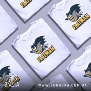 Футболка флетмен білого кольору, зображена з фронтального ракурсу на манекені, фон світло-сірий, принт з персонажем у костюмі Бетмена, що летить, з написом 'FLATMAN' під ним.