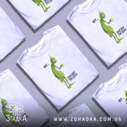 Футболка фу люди. Біла футболка з принтом, на якому зображений зелений персонаж з чашкою в руці. Фон світлий, ракурс зліва, деталі принта чіткі, текст поруч з персонажем: 'ФУ... ЗНОВУ ЛЮДИ!'