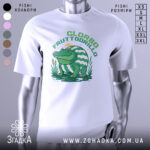 Футболка Glorbo Fruttodrillo білого кольору, зображена з фронтального ракурсу на манекені, фон нейтральний, принт зображає зеленого крокодила, що сидить на воді, з аркушем з водяних лілій і смугастим панцирем.