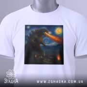 Футболка Ґодзілла Ван Гог, біла футболка, складена на столі, фон світло-сірий, принт з Ґодзіллою, що дихає вогнем, з етикеткою на комірці.