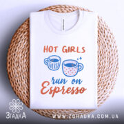 Футболка гарячі дівчата, біла, складена на плетеній кошику, фон світло-сірий, принт з двома чашками кави та текстом 'run on Espresso' у яскравих кольорах.