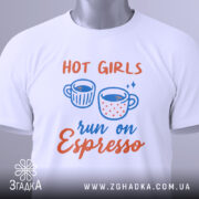 Футболка гарячі дівчата, біла, складена на столі, фон світло-сірий, принт з двома чашками кави та текстом 'run on Espresso', з етикеткою на комірці.