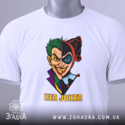 Футболка гарлі джокер білого кольору, розкладена на поверхні, з принтом, що зображає Джокера та Харлі Квін, з текстом 'HER JOKER', на футболці є етикетка з зеленим шнурком, фон світло-сірий.