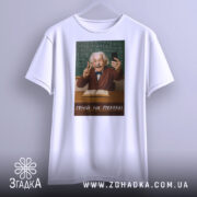 Футболка геній на перерві. Біла футболка з принтом, на якому зображений усміхнений чоловік з сивим волоссям, що тримає телефон і показує знак миру. Фон складається з зеленої дошки з формулами, а текст на футболці: 'ГЕНІЙ НА ПЕРЕРВІ'.