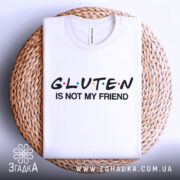 Футболка глютен білого кольору, зображена на плетеній кошику, фон світло-сірий, принт чорного кольору з написом 'GLUTEN IS NOT MY FRIEND' та кольоровими крапками.