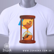 Футболка година війни, біла, зображена на столі, фон світло-сірий, принт з пісочним годинником, на якому одна частина з солдатом, а інша з людиною, що працює на ноутбуці, з етикеткою.