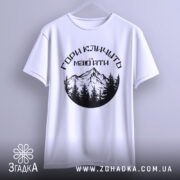 Футболка гори кличуть, біла, зображена з фронтального ракурсу, на фоні світло-сірого градієнту, принт з чорними горами та лісом, текст українською мовою.