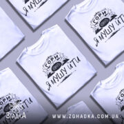 Футболка гори кличуть, білого кольору, зображена на манекені, фон світло-сірий, принт чорного кольору з написом 'ГОРИ КЛИЧУТЬ Я МУШУ ЙТИ' та зображенням гір.