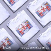 Футболка графіки відключень, білого кольору, зображена на манекені, фон нейтральний, принт з трьома Санта Клаусами, які обговорюють графіки відключень, текст на принті українською мовою.