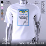 Футболка грамота, біла, зображена на манекені, фон світлий, принт з синьо-жовтим гербом України та текстом "ГРАМОТА".