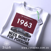 Футболка гроші на машину, біла футболка на столі, ракурс зверху, фон світло-сірий, принт з написом '1963 NEED MONEY FOR PORSCHE' та зображенням автомобіля Porsche, на футболці є етикетка.