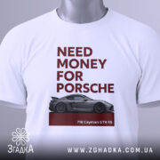 Футболка гроші на Porsche, біла, зображена на столі, фон світло-сірий, принт з текстом 'NEED MONEY FOR PORSCHE' червоного кольору та зображенням автомобіля Porsche 718 Cayman GT4 RS, на комірці є етикетка.