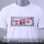 Футболка гроші не сплять, біла, складена на столі, фон світлий, принт у вигляді доларової банкноти з червоним написом "ГРОШІ НІКОМІ НЕ СПІЛЯТЬ", на комірці є етикетка.