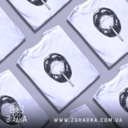 Футболка губи льодяник, біла, зображена на манекені, фон нейтральний, принт чорного кольору з зображенням губ і льодяника.