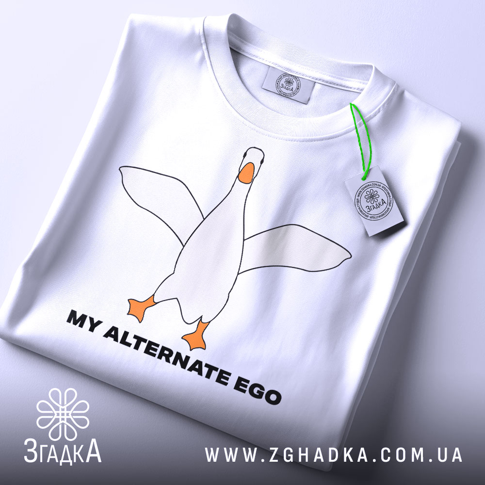 Футболка гусак альтер его, біла, зображена з верхнього ракурсу, на фоні світло-сірого кольору, принт з гусаком в центрі, текст 'MY ALTERNATE EGO' чорного кольору, на футболці є етикетка з зеленим шнурком.