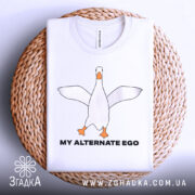Футболка гусак альтер его, біла, зображена зверху, на фоні світло-сірого кольору, принт з гусаком в центрі, текст 'MY ALTERNATE EGO' чорного кольору, футболка лежить на плетеній основі.