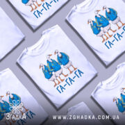 Футболка гуси га га га біла, зображення трьох гусей у синіх худі, стоять в ряд, принт яскравий, текст "ГА-ГА-ГА" під ними, фон світлий.