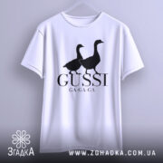 Футболка гуси мем, біла, підвішена, фронтальний ракурс, фон світло-сірий, принт з двома чорними гусями та написом 'GUSSI GA-GA-GA'.