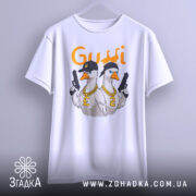 Футболка гуси в кепках білого кольору, підвішена на вішалці, фон світло-сірий, принт з двома гусями в кепках та золотими ланцюгами, один гусак тримає пістолет.