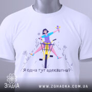 Футболка я адекватна, білого кольору, зображена в складеному вигляді на світлому фоні, принт з дівчиною на велосипеді, яка тримає квіти, текст під малюнком: 'Я одна тут адекватна?', на футболці є етикетка з логотипом.