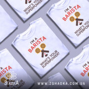 Футболка я бариста, біла, зображена з фронтального ракурсу, фон нейтральний, принт містить жовті кавові порції та текст "I'M A BARISTA" червоного кольору, під ним напис "WHAT'S YOUR SUPERPOWER?" коричневого кольору.