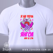 Футболка я янгол, біла, складена на поверхні, фон світлий, принт з ангелом та написом 'Я на 98% янгол, але ще 2%', присутня етикетка з зеленим шнурком.