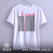 Футболка я інший. Біла футболка з коротким рукавом, підвішена на вішалці, зображена з фронтального ракурсу. На футболці чорні вертикальні смуги з червоною написом 'Я інший'. Фон світло-сірий.