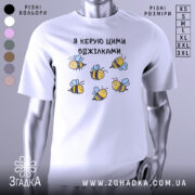 Футболка я керую бджілками, білого кольору, зображена з фронтального ракурсу на манекені, фон світло-сірий, принт з малюнками бджілок жовтого і чорного кольорів з блакитними крилами.