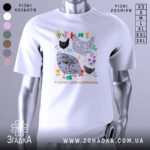 Футболка я керую цими курочками. Біла футболка з коротким рукавом, зображена з фронтального ракурсу на манекені. На фоні світло-сірий колір. Принт містить малюнки курей та квітів, виконаний у яскравих кольорах, з текстом внизу.