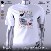 Футболка я керую цими курочками. Біла футболка з коротким рукавом, зображена з фронтального ракурсу на манекені. На фоні світло-сірий колір. Принт містить малюнки курей та квітів, виконаний у яскравих кольорах, з текстом внизу.