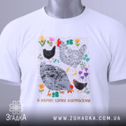 Футболка я керую цими курочками. Біла футболка, зображена зверху, з коротким рукавом. Фон світло-блакитний. Принт з малюнками курей та квітів, яскраві кольори, з текстом внизу. На футболці є етикетка з зеленим шнурком.