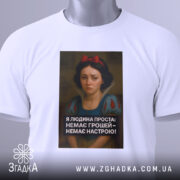 Футболка я людина проста. Біла футболка, складена на поверхні, з видимим етикеткою. Принт з дівчиною в центрі, текст чорного кольору під зображенням. Фон світлий, без зайвих деталей, футболка виглядає охайно.