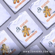 Футболка я не ображаюся, білого кольору, зображена з фронтального ракурсу на манекені, фон світло-сірий, принт з жовтою лялькою вуду та текстом "Я взагалі не ображаюся!" у помаранчевому та темно-синьому кольорах.