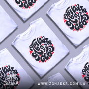 Футболка я обираю себе. Біла футболка на манекені, з коротким рукавом, з принтом чорного кольору, оточеним червоними сердечками. Фон світло-сірий, що підкреслює яскравість принта.