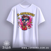 Футболка я переможець, білого кольору, підвішена на вішалці, фон світло-сірий, принт з хлопчиком у сонцезахисних окулярах, який піднімає руку вгору, з написом 'Я - переможець!' та яскравими зірочками.