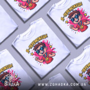 Футболка я переможець, білого кольору, зображена на манекені, фон світло-сірий, принт з веселим хлопчиком у сонцезахисних окулярах, який піднімає руку вгору, з написом 'Я - переможець!' та яскравими зірочками.